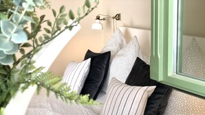 A cozy bedroom with a sloped ceiling, a green wall, and a window with a view of the sky.