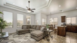 A spacious living room with a sectional sofa, a dining area, and a kitchen with granite countertops. - House with Community Pool and Putting Green (Las Cruces)