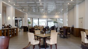 A spacious indoor dining area with multiple tables and chairs, a reception desk, and a staircase leading to an upper level. - Reddoorz Premium @ Bandung City Center (Bandung)