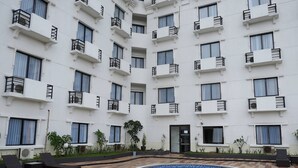 A multi-story hotel with balconies, a swimming pool, and outdoor seating. - Reddoorz Premium @ Bandung City Center (Bandung)