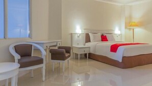 A hotel room with a bed, two nightstands, a desk, two chairs, and a lamp. - Reddoorz Premium @ Bandung City Center (Bandung)