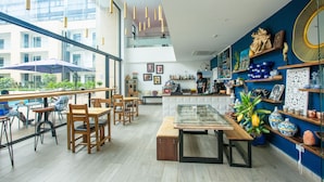 A modern cafe with wooden furniture, a glass display case, and decorative items on shelves. - Embassy Gardens by Morninglife Luxury (Accra)