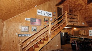 Un intérieur en bois avec un escalier, un coin cuisine et un panneau indiquant la direction du fleuve.