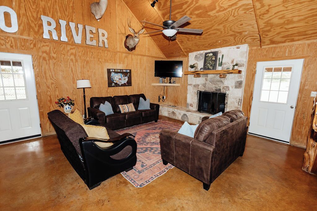 A rustic interior with a wooden ceiling, a fireplace, a sofa, and a television.