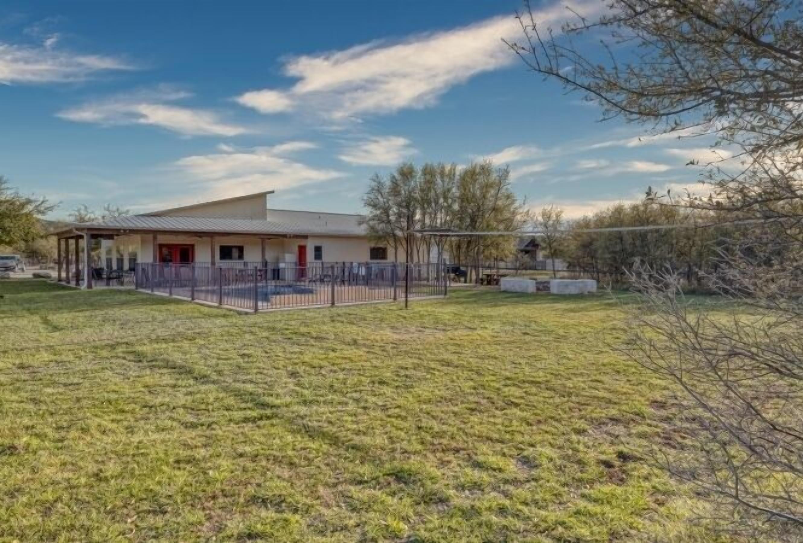 A building with a flat roof, a covered porch, and a fenced yard.