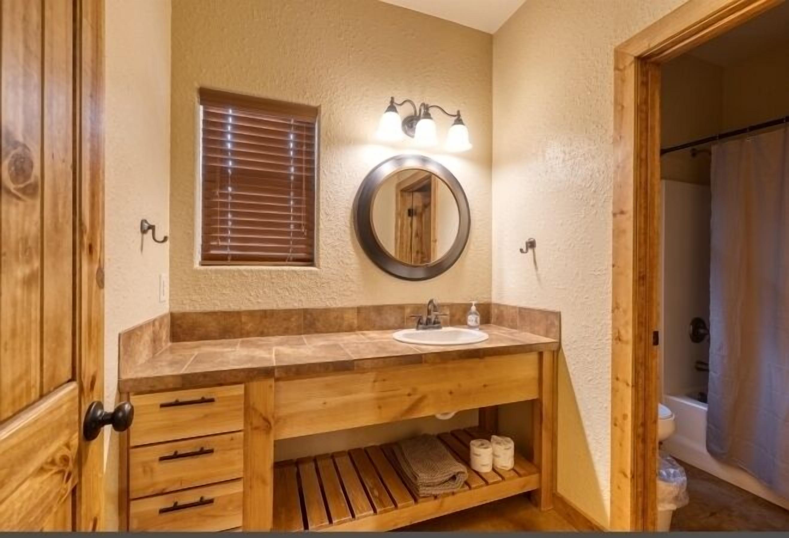 A bathroom with a wooden vanity, a round mirror, and a sink.