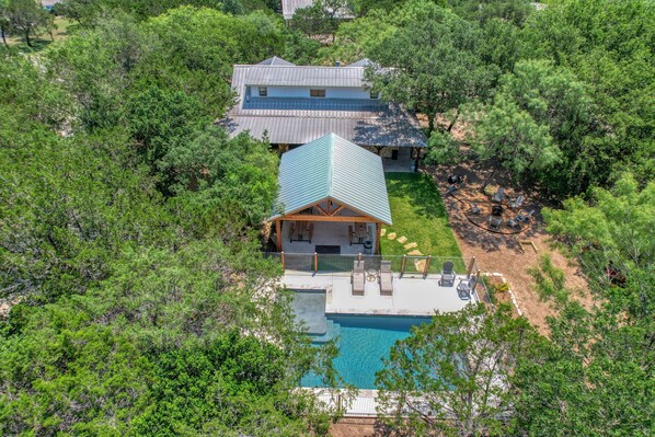 Uma casa com piscina cercada por árvores densas.