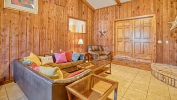 Una sala de estar acogedora con paredes de madera, un sofá de cuero, una mesa de centro de cristal y una decoración con forma de estrella en la pared.