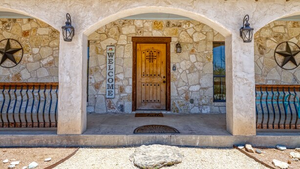 A stone building with a wooden door, a 'WELCOME' sign, and two lanterns. - Beautiful and spacious home with a pool (Concan)