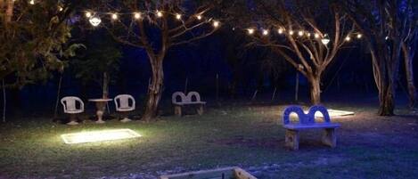An outdoor area with string lights, wooden benches, and a small table.