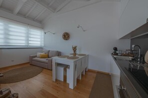 A modern living room with a sofa, a dining table, and a kitchen area with a stove.