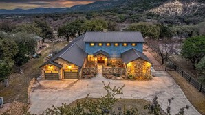 Una casa grande con fachada de piedra, varios portones de garaje y un camino de entrada.