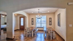 A spacious dining area with a high ceiling and a chandelier, featuring a large table and several chairs. - Heartstone Subdivision with a pool (Concan)