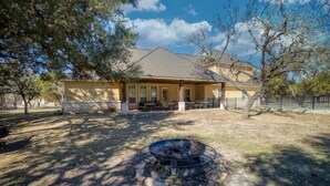 A building with a patio area, outdoor seating, and a fire pit. - Heartstone Subdivision with a pool (Concan)