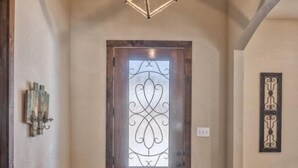 A hallway with a wooden door featuring a decorative glass panel. - Heartstone Subdivision with a pool (Concan)