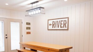 Een houten picknicktafel met bankjes in een kamer met witte muren en een gepolijste vloer.