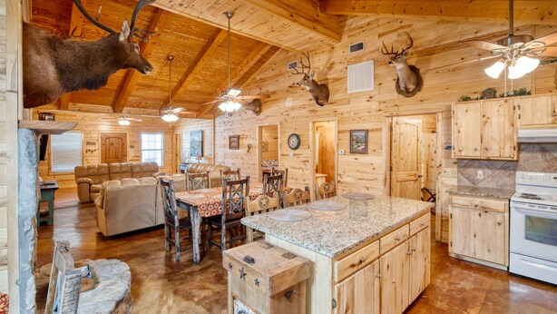 A rustic cabin interior with wooden walls, a large kitchen island, and mounted deer heads. - Beautiful home in the Comanche Crossing Subdivision (Concan)