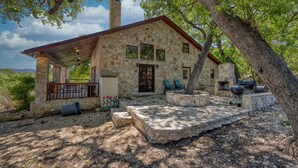 A stone house with a covered patio, outdoor seating, and a barbecue area. - Beautiful home in the Comanche Crossing Subdivision (Concan)