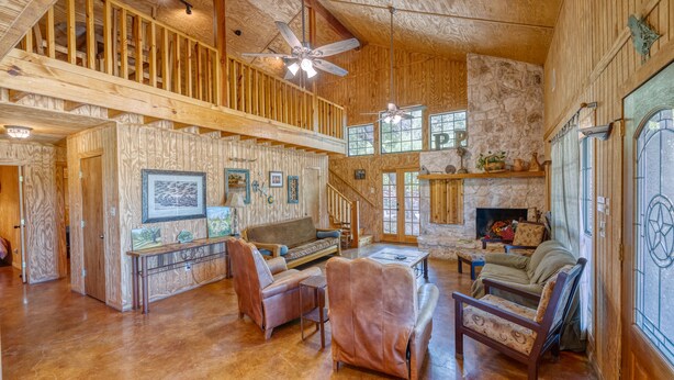 A spacious wooden interior with a high ceiling, a staircase, and a fireplace. - Beautiful home in the Comanche Crossing Subdivision (Concan)