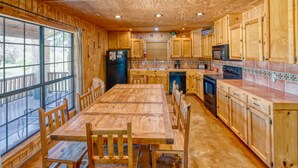A spacious kitchen with wooden cabinets, a large dining table, and a view through the window. - Beautiful home in the Comanche Crossing Subdivision (Concan)