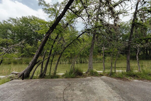 A concrete viewing platform overlooking a body of water with trees and greenery in the background. - River Front in Comanche Crossing (Concan)