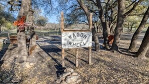 A wooden sign with the text "WAGON WHEEL" and "1775" indicating a historical site. - Small home in a quiet neighborhood (Concan)