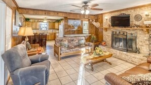 A living room with a sofa, armchair, and coffee table, a fireplace, and a television. - Small home in a quiet neighborhood (Concan)