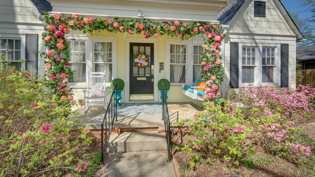 A house with a porch decorated with pink flowers, a black door, and a bench. - 'The Pink Azalea' - Tyler Home w/ Yard + Patio! (Tyler)