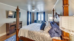 A spacious bedroom with a large bed, a ceiling fan, a wooden dresser, and a television on the wall. - 'The Pink Azalea' - Tyler Home w/ Yard + Patio! (Tyler)