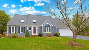 A two-story house with a grey roof, a red front door, and a garage. - Close to Wequaquet Lake, beautiful and spacious cottage (Barnstable)