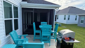 A patio with turquoise outdoor furniture, a grill, and a covered area.