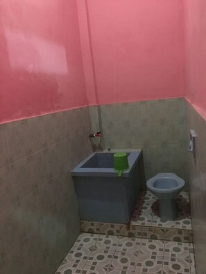 A small bathroom with a toilet and a sink. - Hotel Trias Parangtritis by Zuzu (Parangtritis)