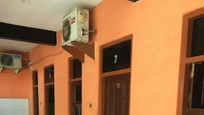 A room with a tiled floor, a wooden door with the number 7, and a table with a green tablecloth. - Hotel Trias Parangtritis by Zuzu (Parangtritis)