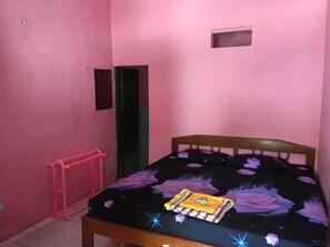 A small, pink-walled room with a wooden bed, a pink ladder, and a green door. - Hotel Trias Parangtritis by Zuzu (Parangtritis)