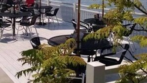 Un espace extérieur aménagé avec des tables et des chaises, une terrasse et une vue sur un plan d’eau.