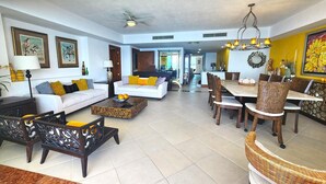 A spacious living area with a dining table and chairs, a sofa set, and a coffee table.