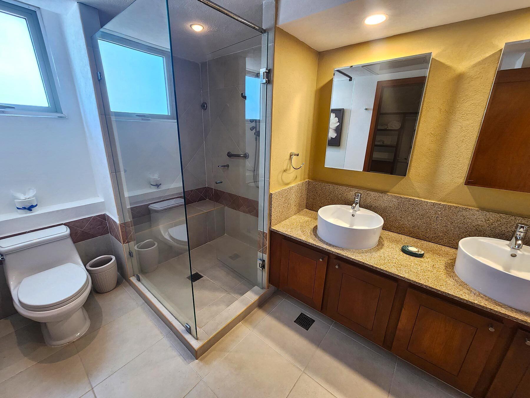 A modern bathroom with a glass-enclosed shower, two sinks, and a large mirror.