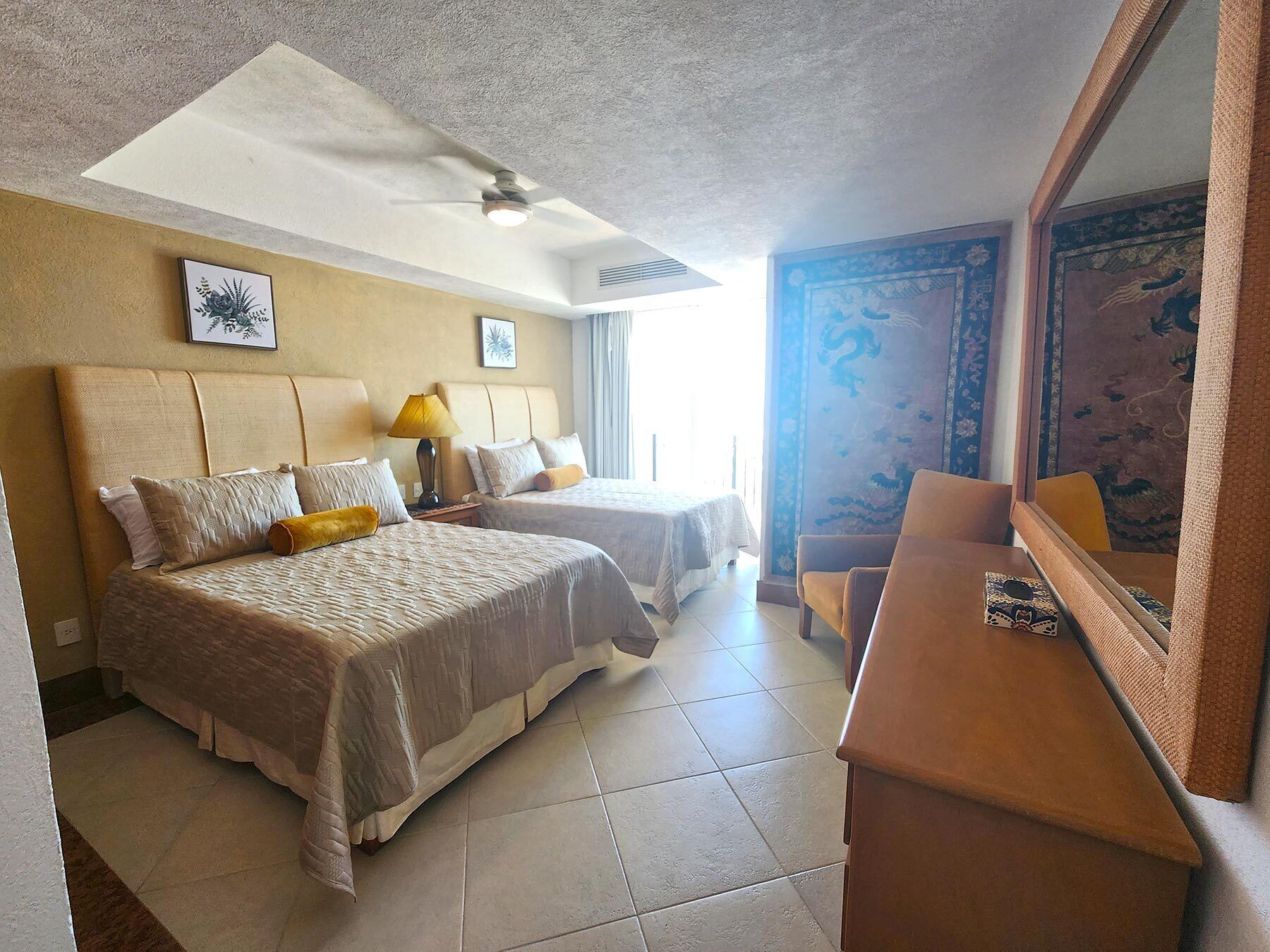 A hotel room with two beds, a desk, and a chair.