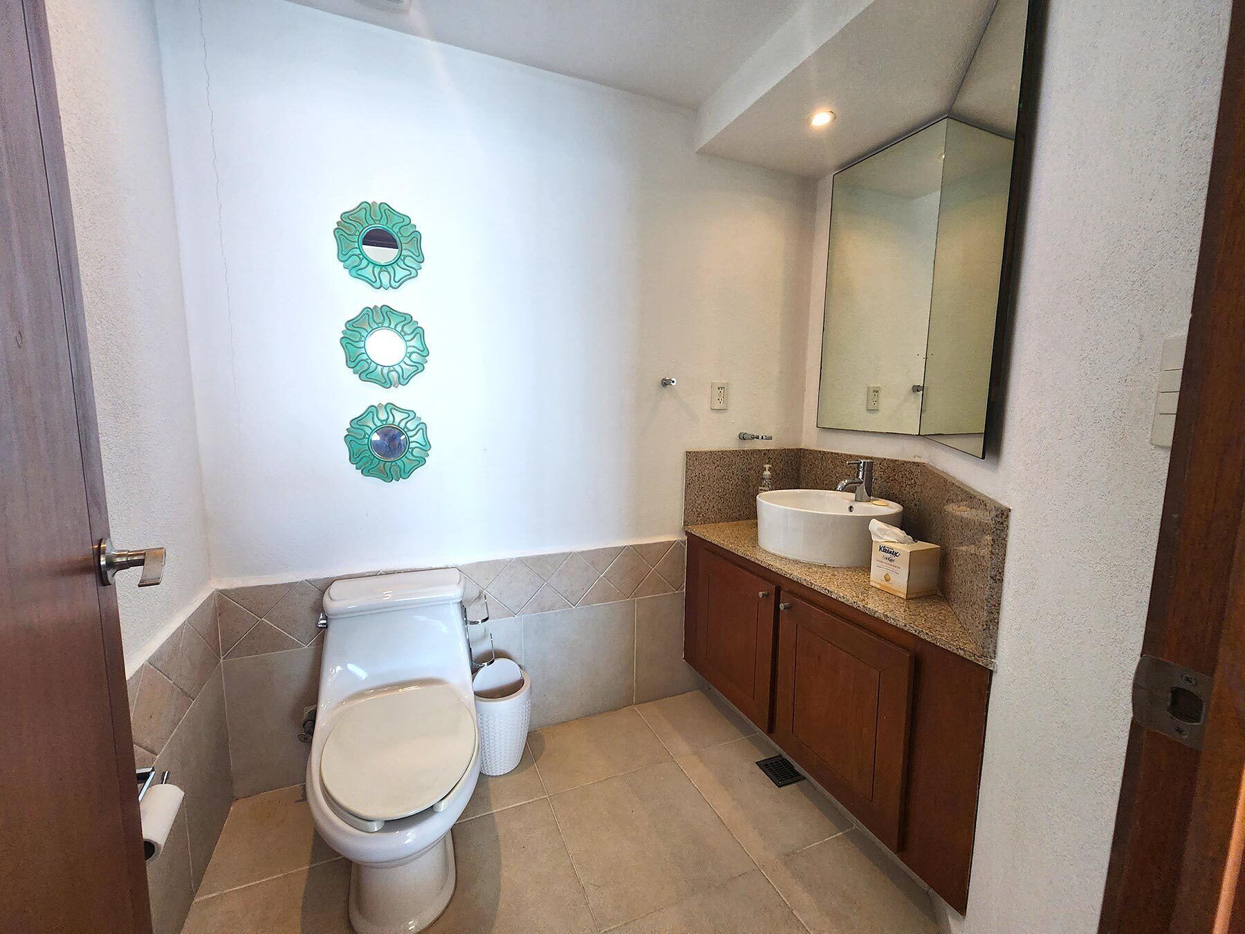 A bathroom with a toilet, sink, and mirror.