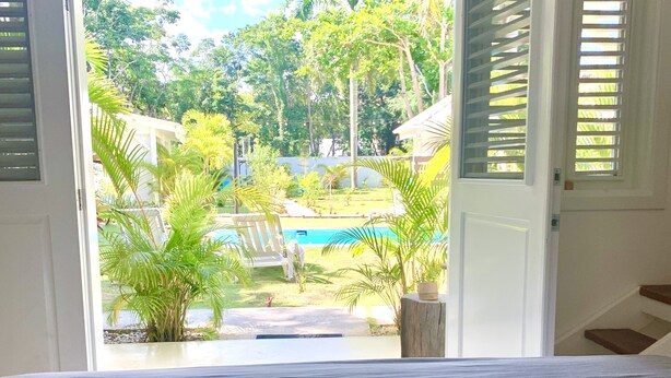 A bedroom with a bed, a view of a swimming pool, and a garden. - Punta Popy Boutique Hotel (Las Terrenas)