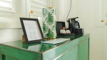 A reception desk with a framed menu, a decorative vase, a coffee machine, and a green cabinet.
