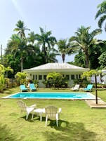 Una piscina al aire libre, sombrillas, sillones reclinables de piscina