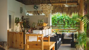 A cozy room with a wooden table, wicker sofa, and a thatched ceiling. - Punta Popy Boutique Hotel (Las Terrenas)