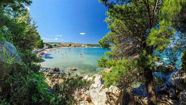 Une plage côtière aux eaux cristallines, bordée d’une côte rocheuse et d’une végétation luxuriante.