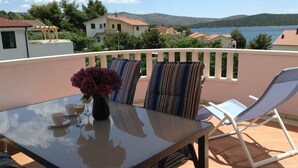 Un balcon avec une table, des chaises et un vase de fleurs.