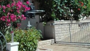 Un immeuble résidentiel à deux étages doté d’un balcon, d’une antenne parabolique et d’une entrée sécurisée par un portail.