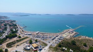 Vista aérea de una zona costera con un puerto deportivo, estacionamientos y edificios.