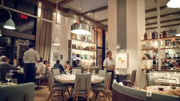 Un restaurant avec des tables rondes, des chaises et des lampes suspendues.