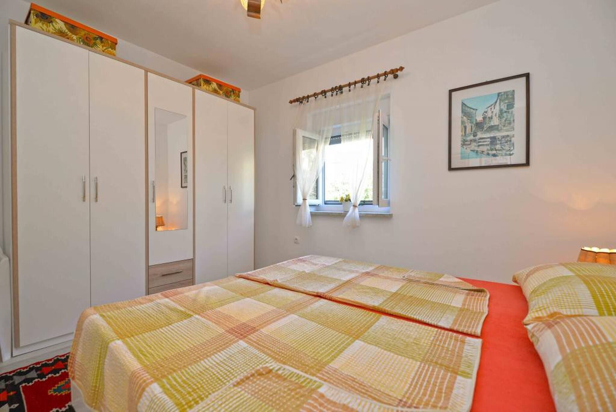 Un dormitorio con cama, armario, ventana con cortinas e imagen enmarcada en la pared.