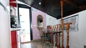 A compact kitchen with a refrigerator, stove, and sink. There is a dining area with a table and chairs. A staircase with a wooden railing is visible. - Holiday Home Serov - four bedroom house (Tisno)